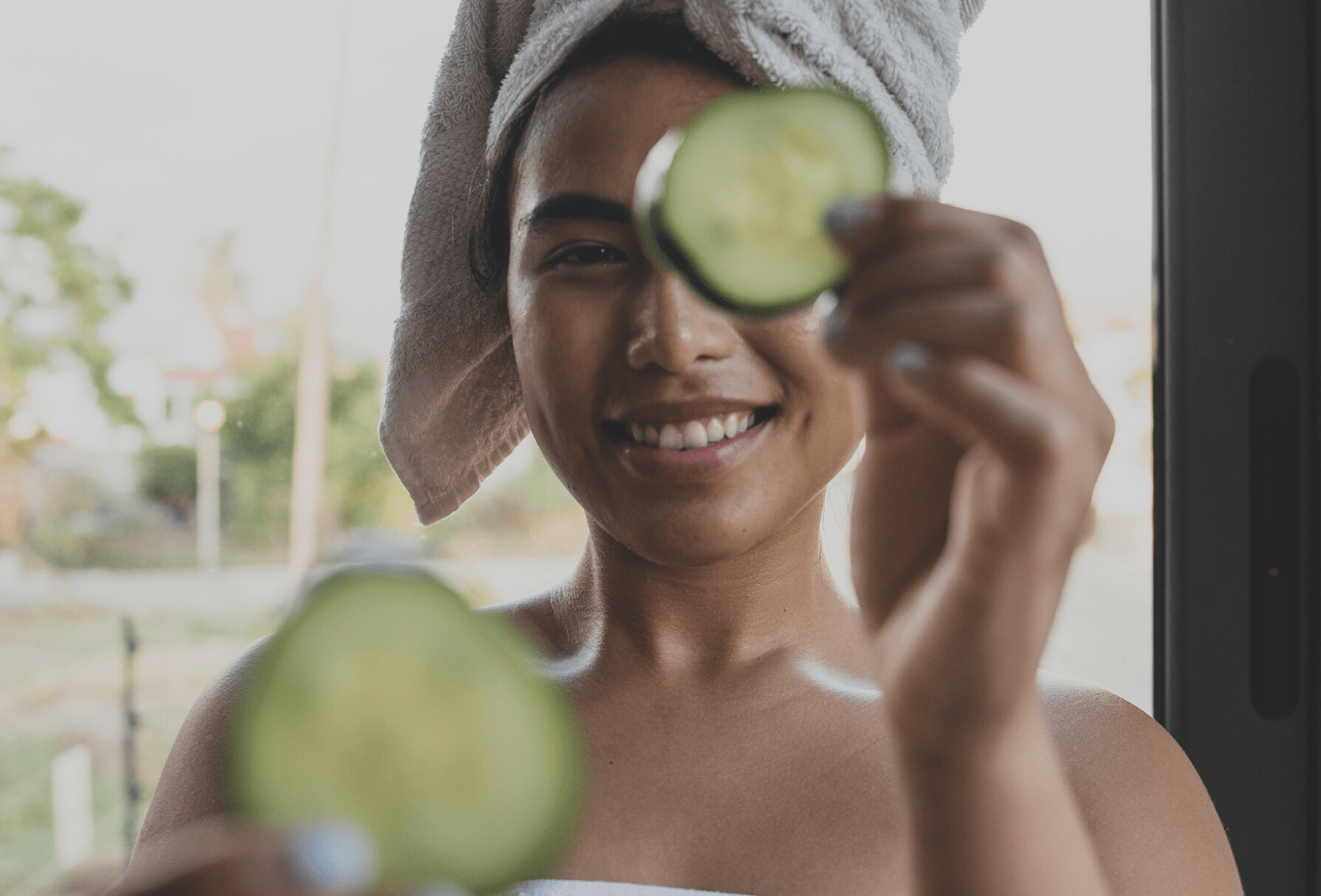 women in towel holding cucumbers 