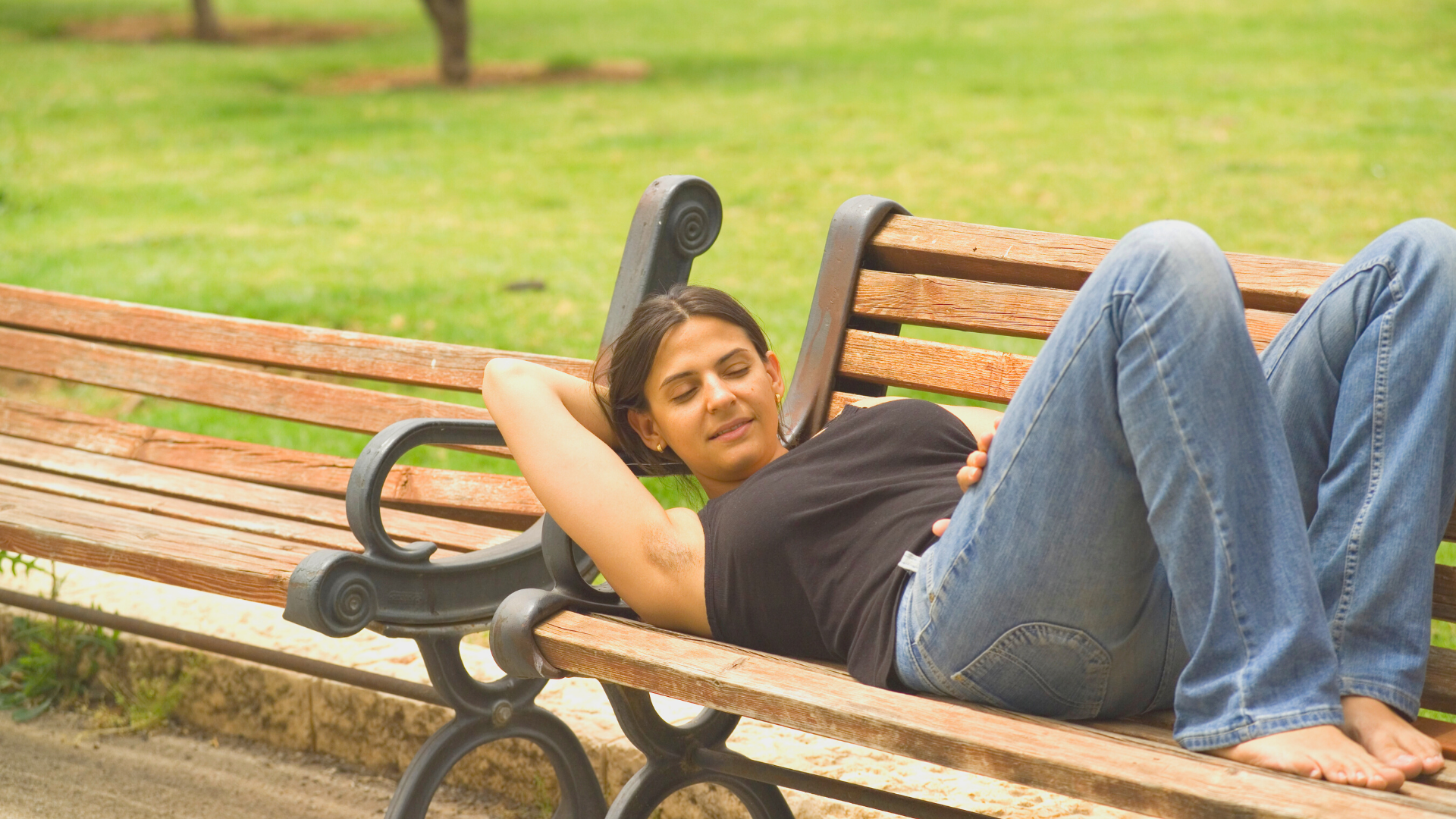 woman daydreaming on park bench outside of nefertem studio