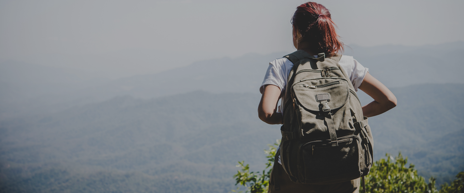 woman standing on mountain with holistic skincare in backpack