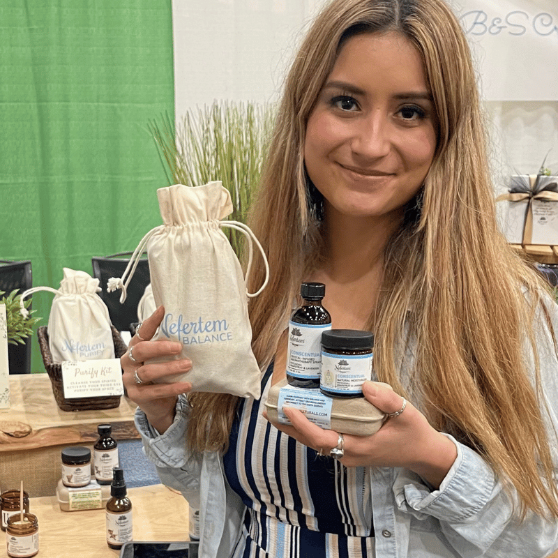 happy young woman holding Nefertem soaps at expo