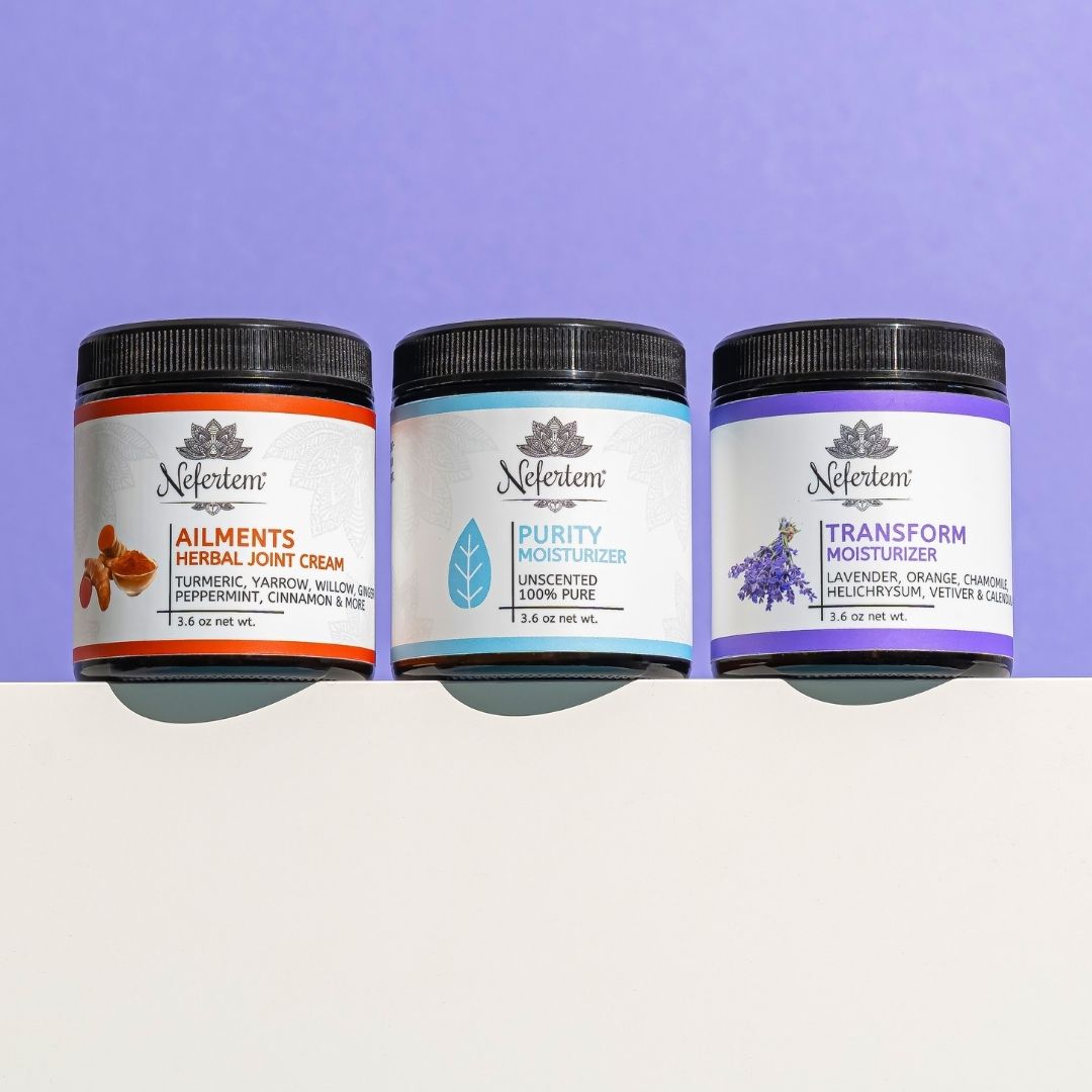 Three Nefertem's tallow moisturizers on a white surface with a purple background