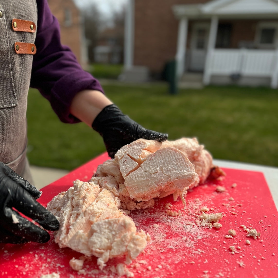 the founder of nefertem tallow skincare chopping up suet for the tallow moisturizers outside on red cutting board