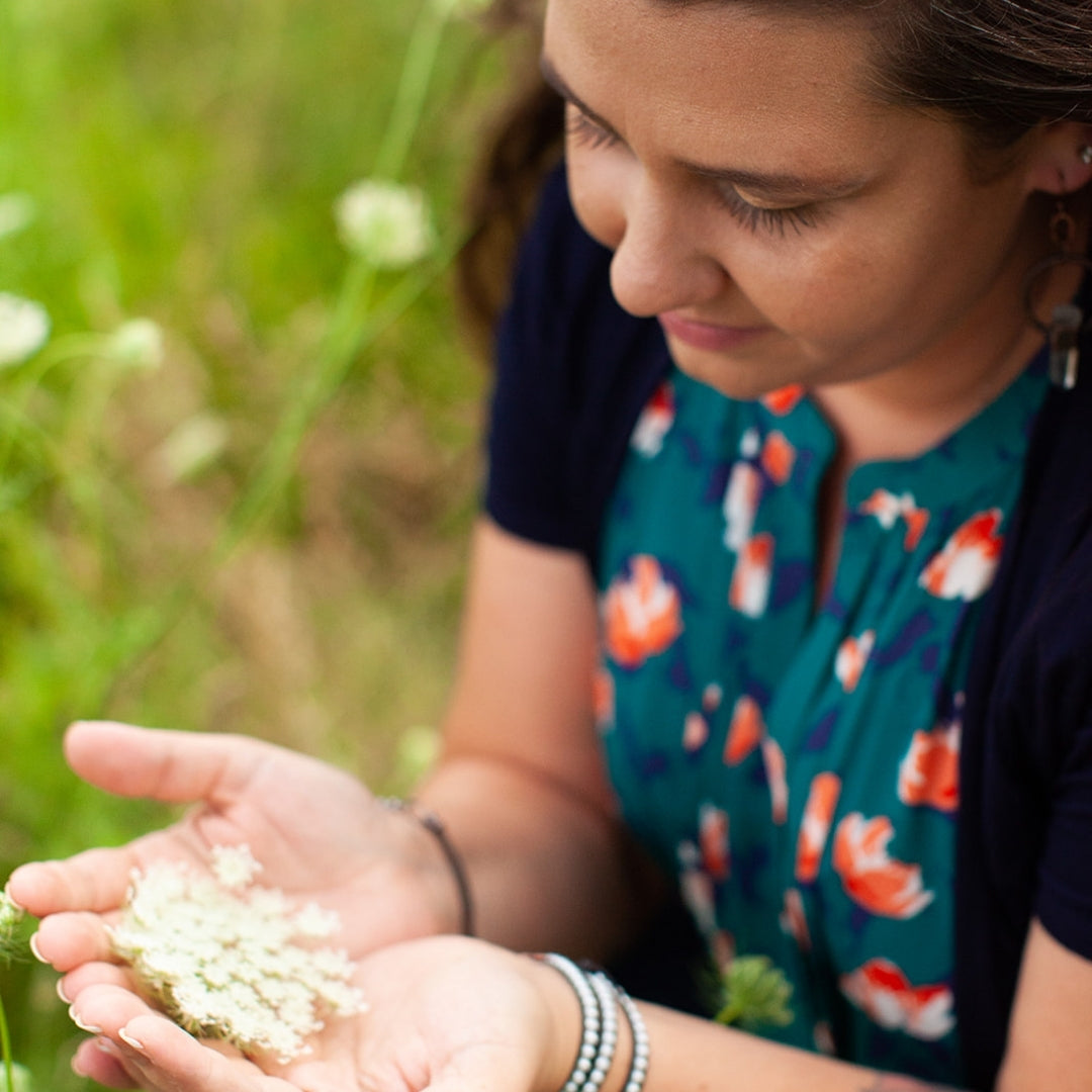 Woman holding white flowers in her hands with a blurred green background